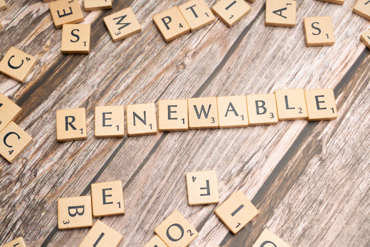 Wooden Scrabble tiles on a wooden table spell Renewable emphasizing sustainability.